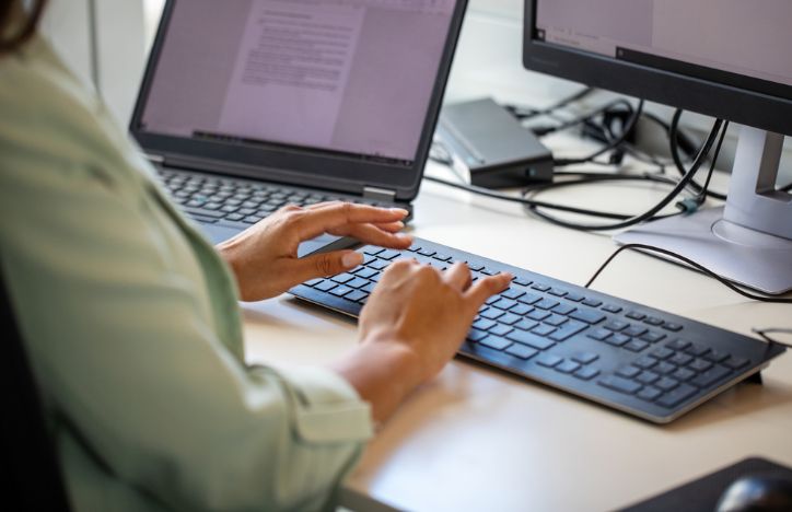 Woman Using Computer With Dual Screen