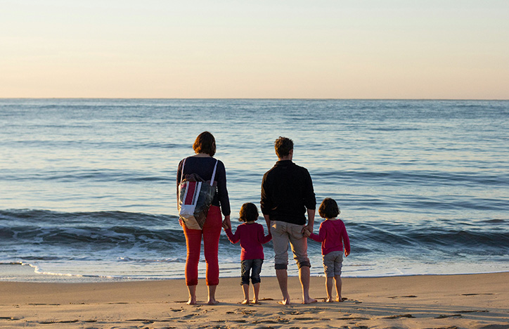 Parents Holding Their Children's Hands At The Beach