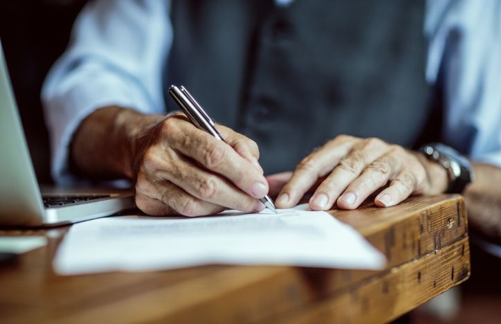 Close Up Of Elderly Man's Hands Signing A Document