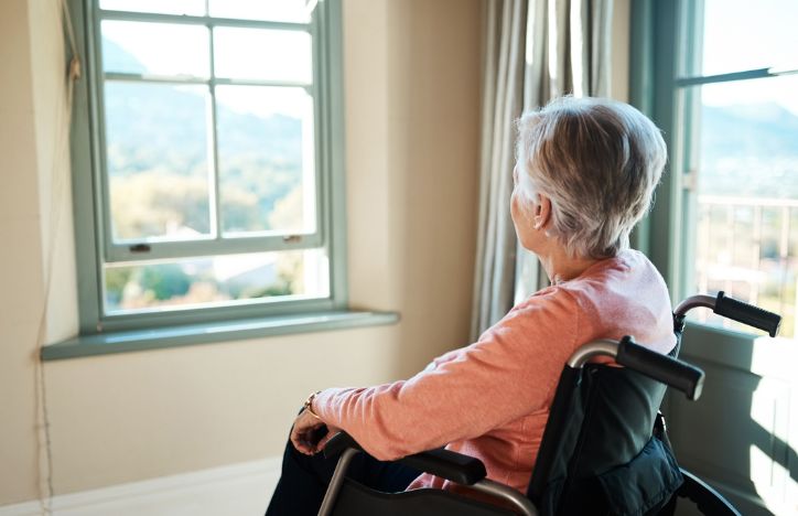 Elderly Woman In A Wheelchair Looking Out Of The Window