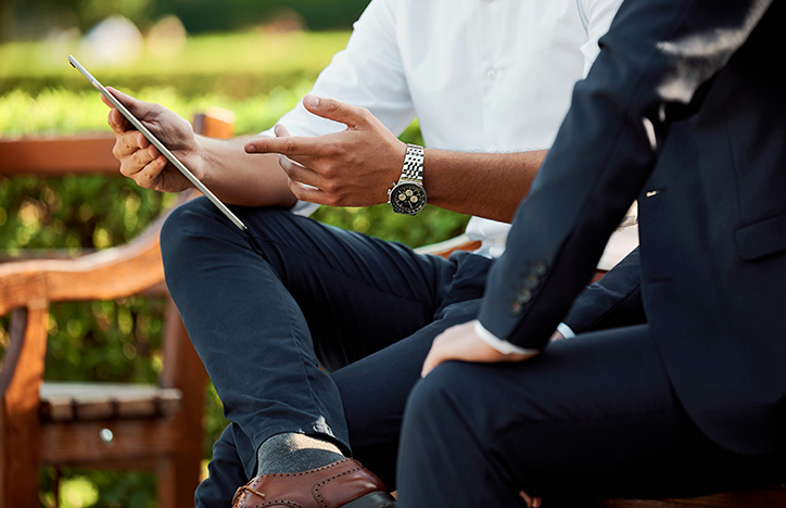 Two Men Looking At A Tablet During A Conversation