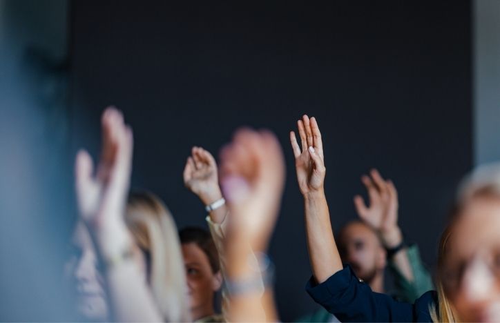 Engaged Audience Raising Hands At Business Event