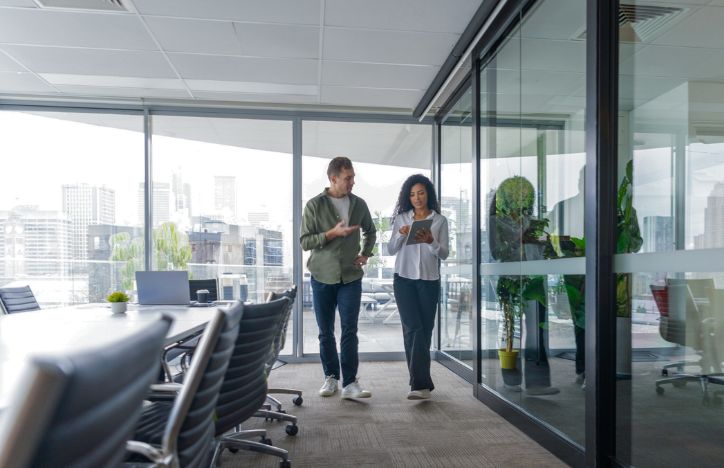 Two People Walking And Talking In An Office