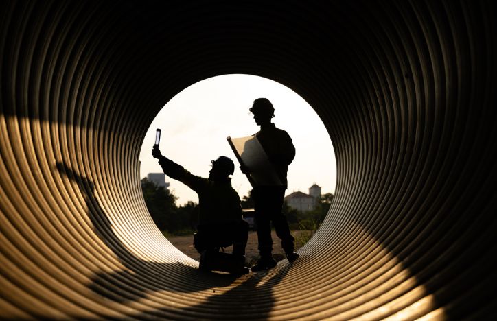 Construction Workers And Engineers Are Working Inside A Large Metal Pipe