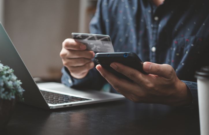 Man At Desk Paying By Card On His Mobile Phone