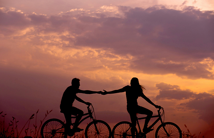 Couple Riding Bikes Holding Hands