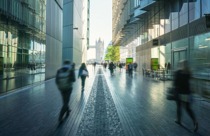 Blurred People Walking Through A Street Of Offices With Tower Bridge In The Background