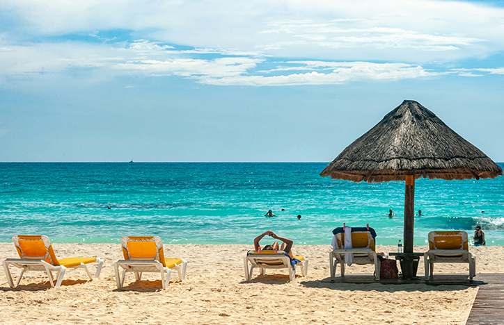 Loungers And A Thatched Umbrella On A Beach