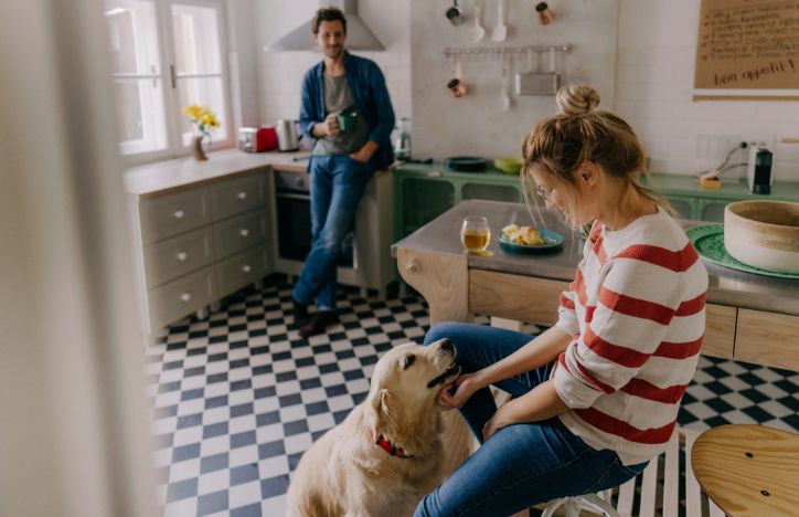 Two People In The Kitchen With Their Dog