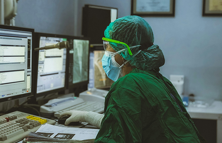 Health Care Worker In Scrubs Looking At A Computer