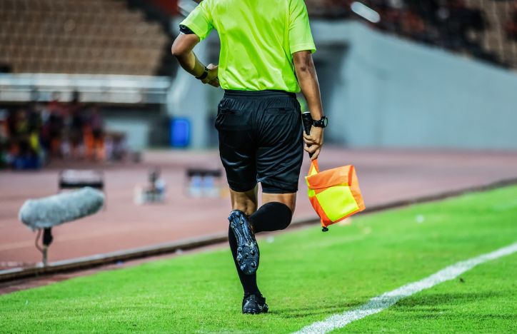 Linesman Running Down Touchline On Football Pitch